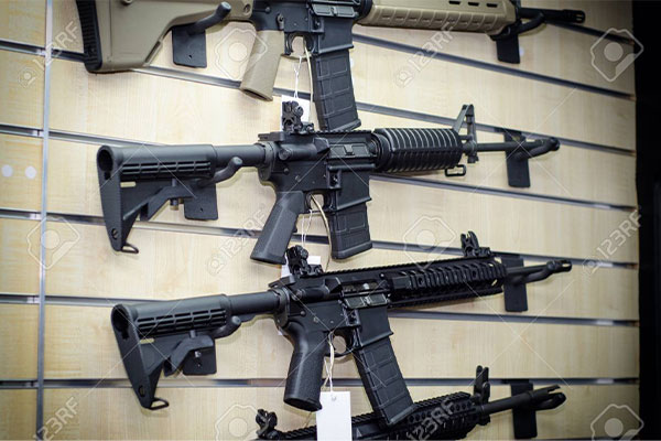 Three black semi-automatic rifles are displayed on a wall rack inside a store.