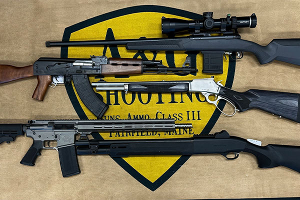 Four different rifles are displayed on a mat with a shooting range logo in the background.